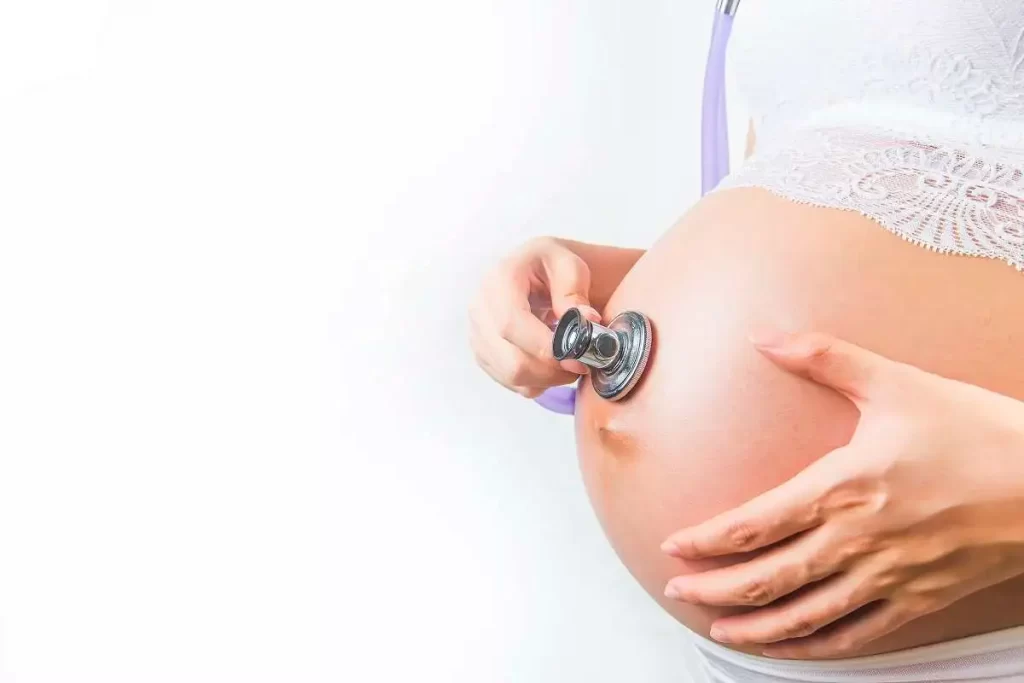 Pregnant woman receiving gentle prenatal monitoring with a stethoscope at Divine Women's Hospital
