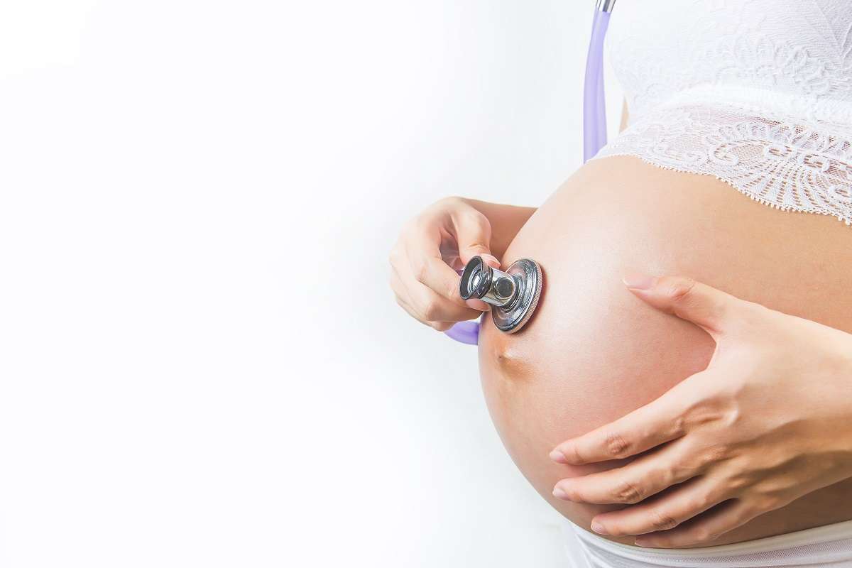 Pregnant woman using stethoscope examining on her baby in her belly